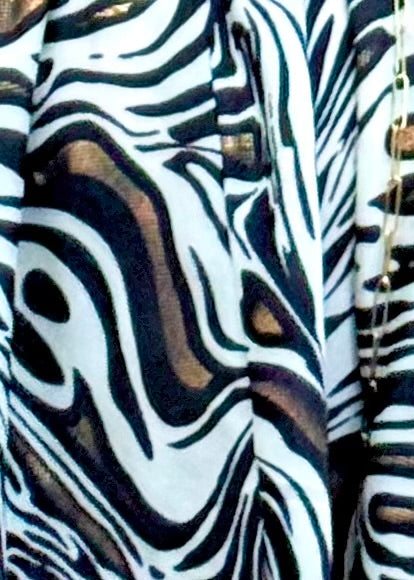 A close-up of a black, white, and brown wavy abstract patterned fabric, resembling a zebra or fluid art print.