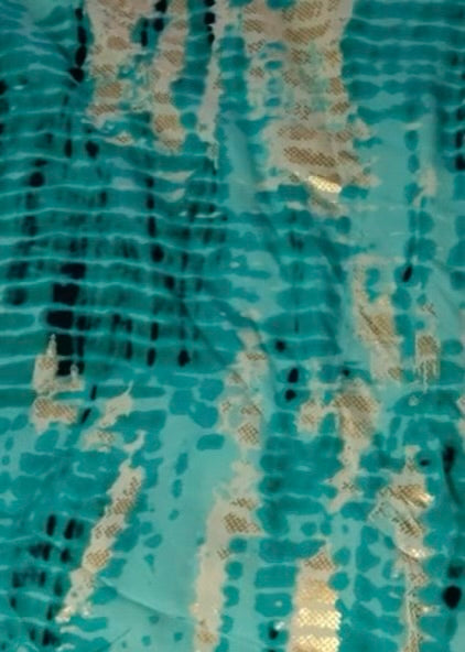 Close-up of a textured fabric with gold and black patterns on a teal background