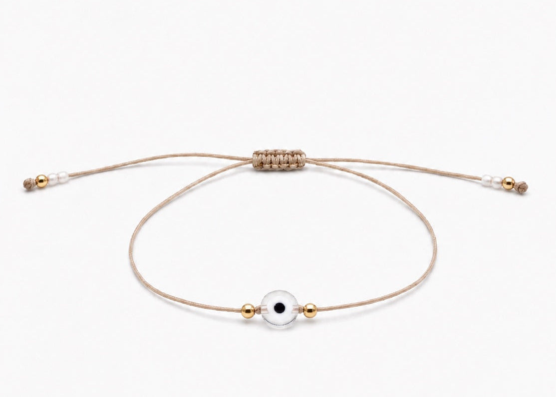 Delicate adjustable bracelet with a small evil eye charm and gold filled beads on a white background