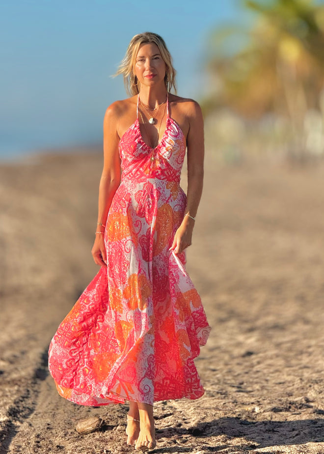 Woman in a colorful dress standing on a sandy beach.