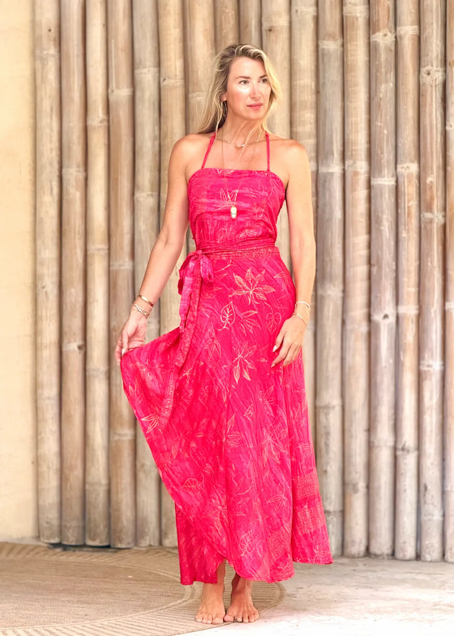 Woman wearing a pink dress with floral patterns against a wooden background