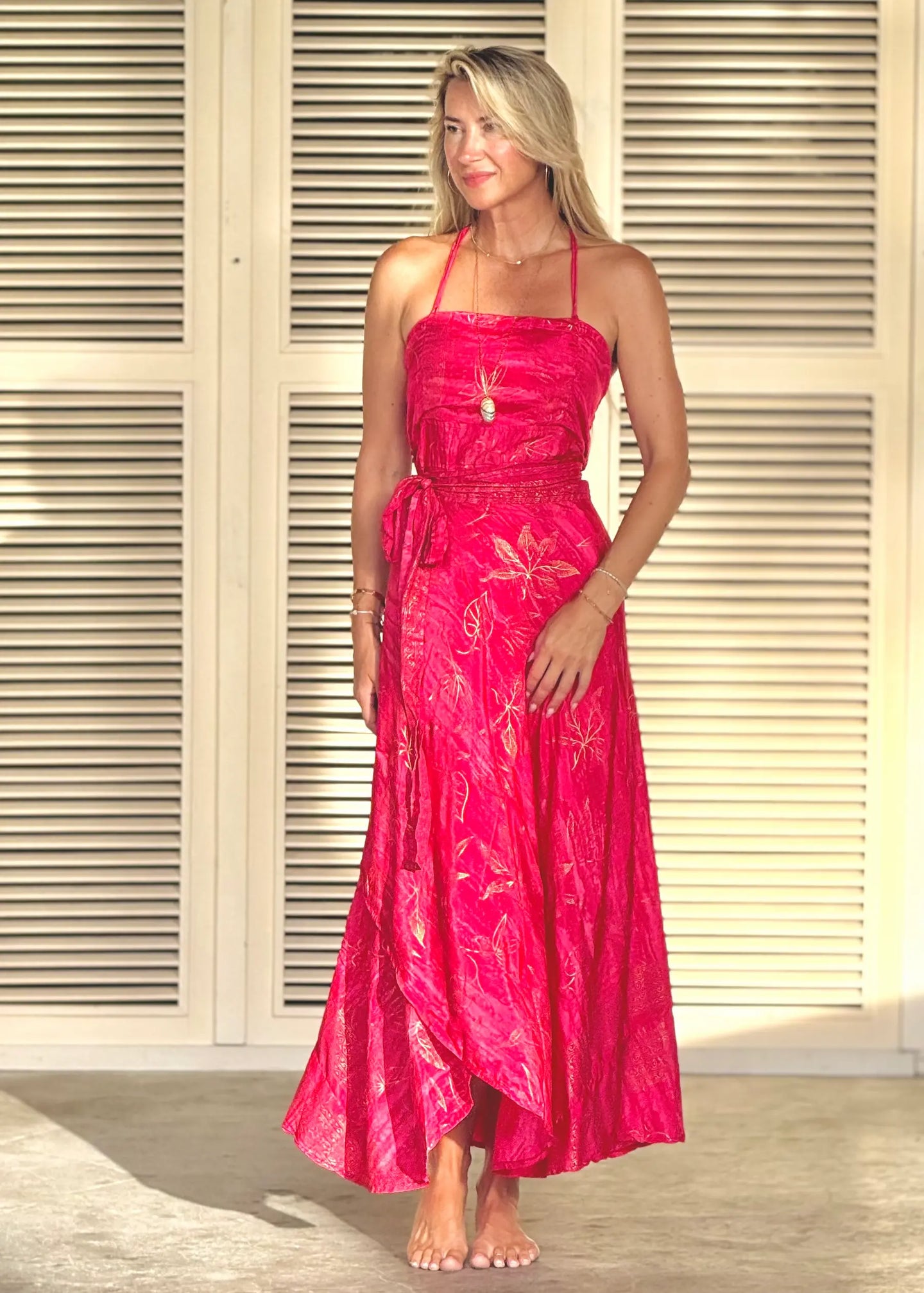 Woman wearing a pink dress standing in front of a neutral background