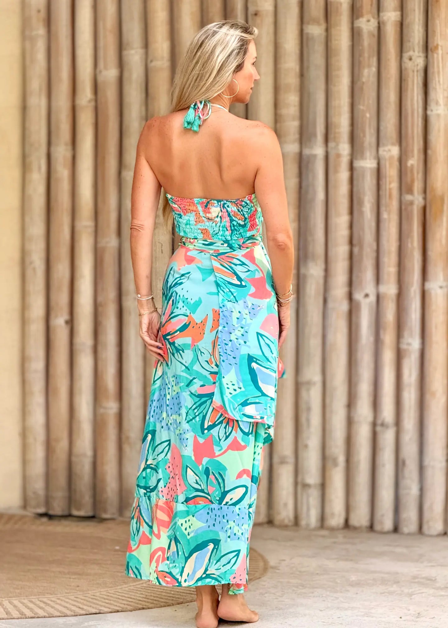 Woman wearing a colorful strapless dress with a floral pattern against a wooden background